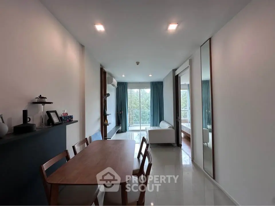 Modern living room with dining area and large windows offering natural light and greenery view.