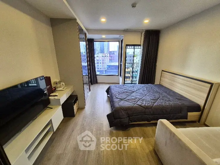 Modern bedroom with city view, featuring sleek furniture and ample natural light.