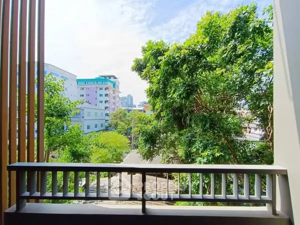 Stunning view from a balcony overlooking lush greenery and urban skyline.