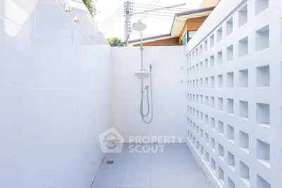 Modern outdoor shower area with sleek white tiles and minimalist design