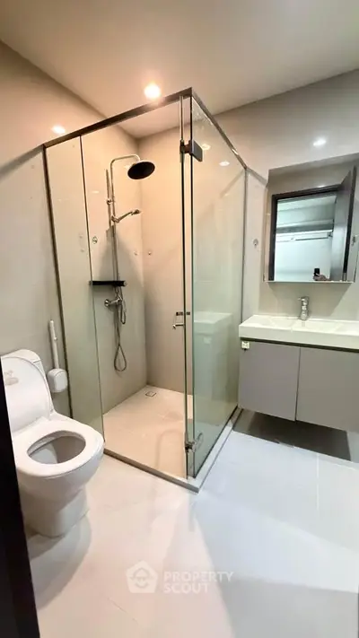 Modern bathroom with glass shower enclosure and sleek fixtures in a contemporary apartment.