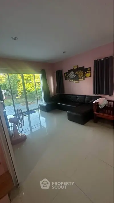 Spacious living room with large windows and garden view, perfect for relaxation and family gatherings.
