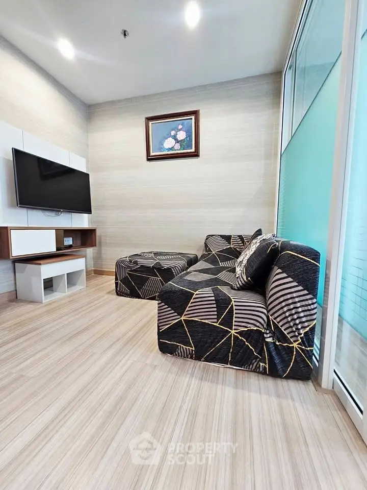 Modern living room with stylish geometric sofa and wall-mounted TV, perfect for cozy relaxation.