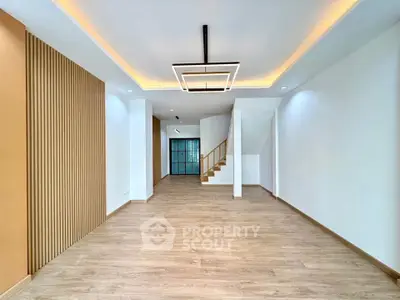 Spacious modern living room with elegant lighting and wooden flooring, perfect for family gatherings.