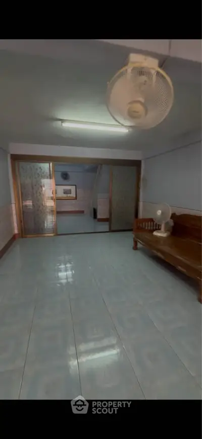 Spacious living room with tiled floor and ceiling fan, ideal for family gatherings.