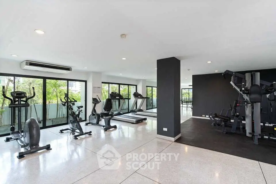 Spacious modern gym with large windows and fitness equipment in a residential building.