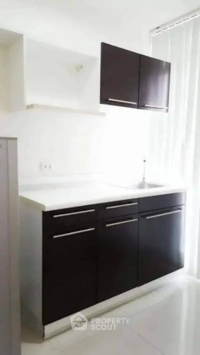Modern kitchen with sleek dark cabinets and bright natural lighting.