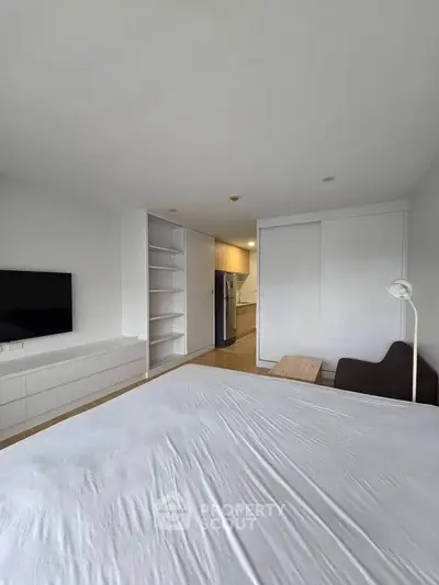 Modern bedroom with built-in storage and sleek kitchen view, perfect for urban living.