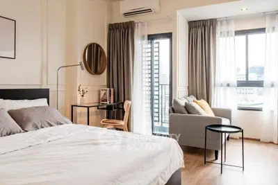 Modern bedroom with stylish decor and city view, featuring cozy seating area and natural light.