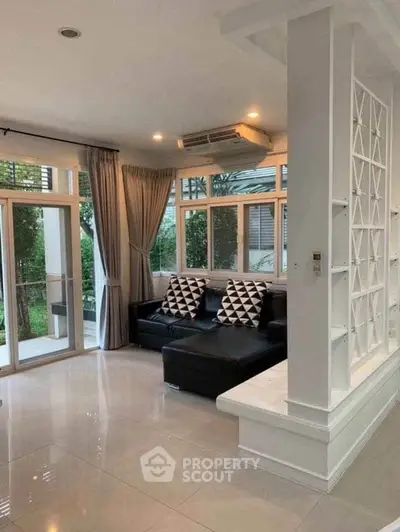 Spacious living room with modern decor and large windows overlooking garden