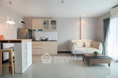 Modern open-plan living room with kitchen, featuring sleek furniture and natural light.