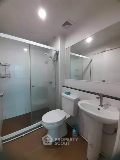 Modern bathroom with glass shower enclosure and sleek fixtures in a contemporary apartment.