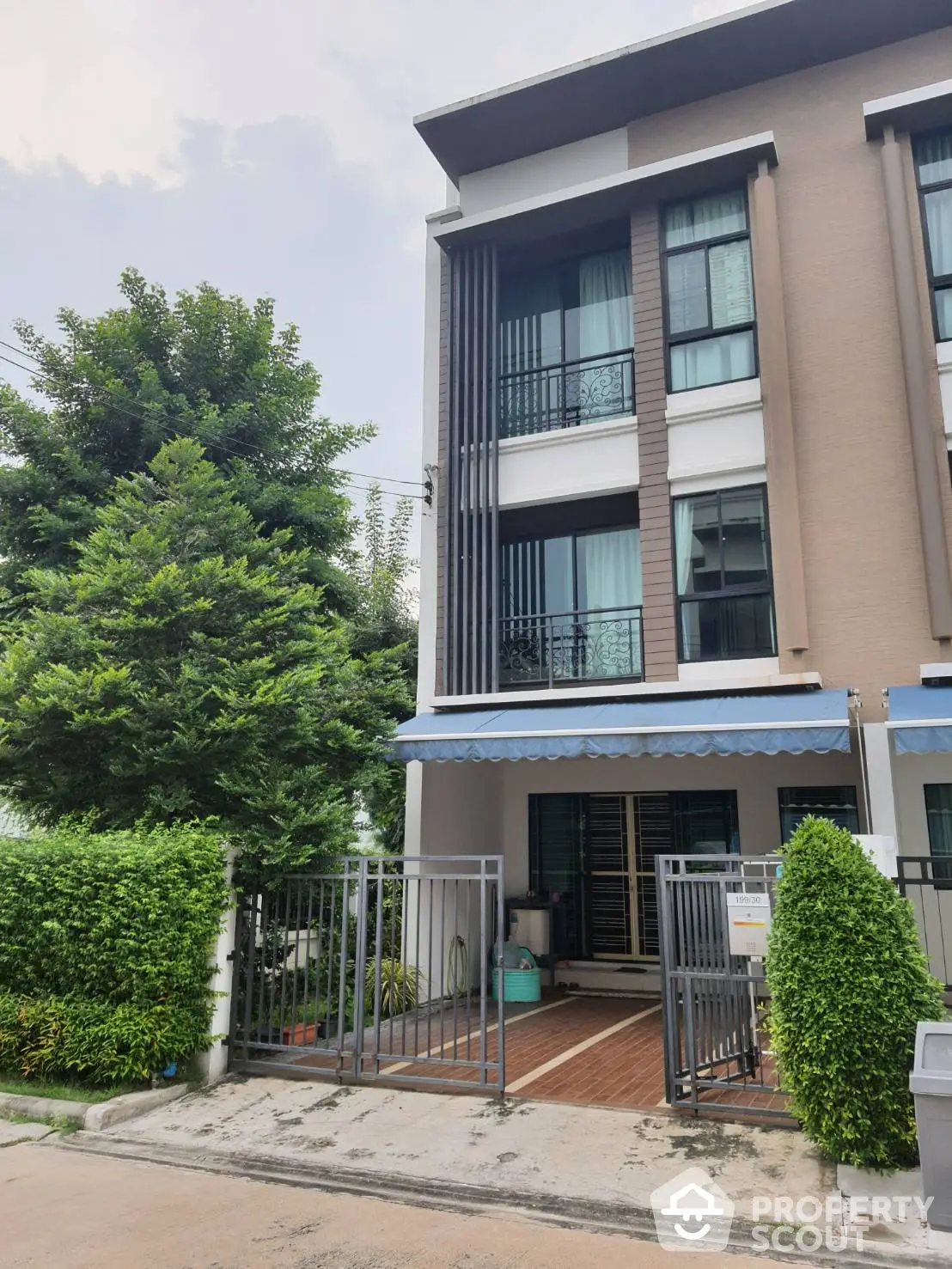 Elegant modern townhouse with spacious balcony and large windows, nestled in a lush green neighborhood, offering a serene urban living experience.