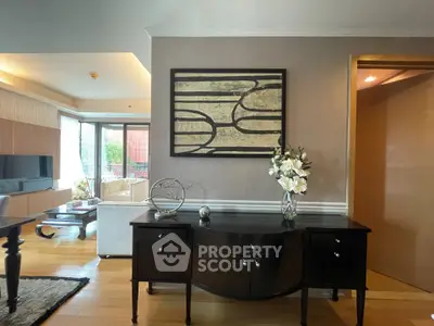 Elegant living room with modern decor and natural light, featuring stylish furniture and art piece.
