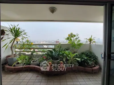 Spacious balcony with lush greenery and city view, perfect for relaxation.