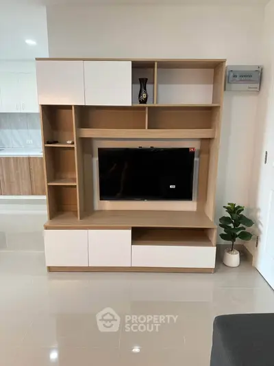 Modern living room with sleek TV unit and open kitchen layout, perfect for contemporary living.