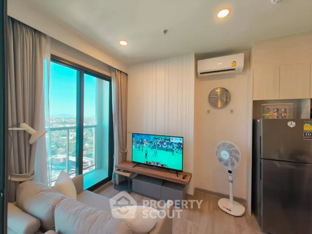 Modern living room with balcony view, air conditioning, and sleek furniture in a high-rise apartment.