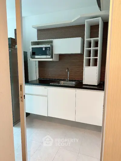 Modern kitchen with sleek white cabinets and built-in microwave