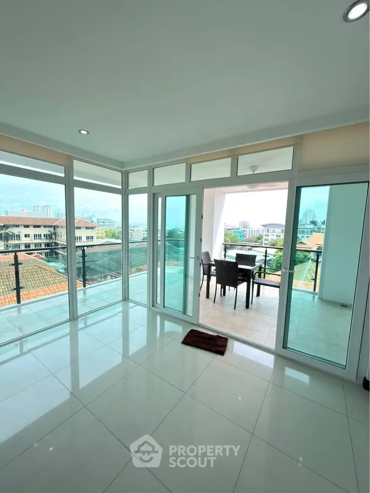 Spacious modern living room with large windows and balcony offering stunning city views.