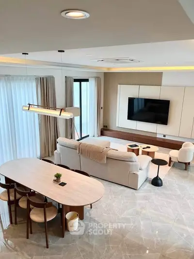 Luxurious modern living room with elegant furniture and large TV, perfect for relaxation and entertainment.