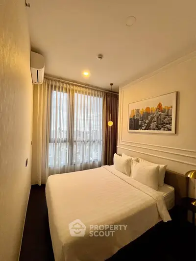 Cozy modern bedroom with city view, featuring elegant decor and natural light through large windows.