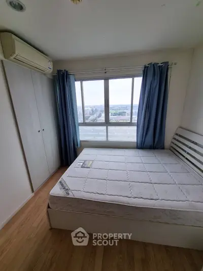 Cozy bedroom with large window and city view, featuring a comfortable bed and ample closet space.