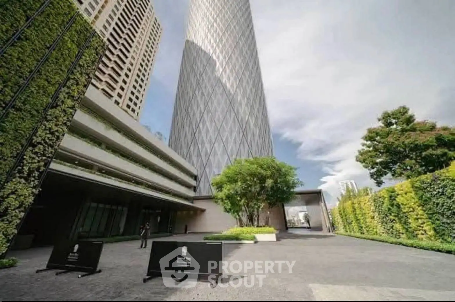 Stunning modern high-rise building with lush green landscaping and spacious entrance.