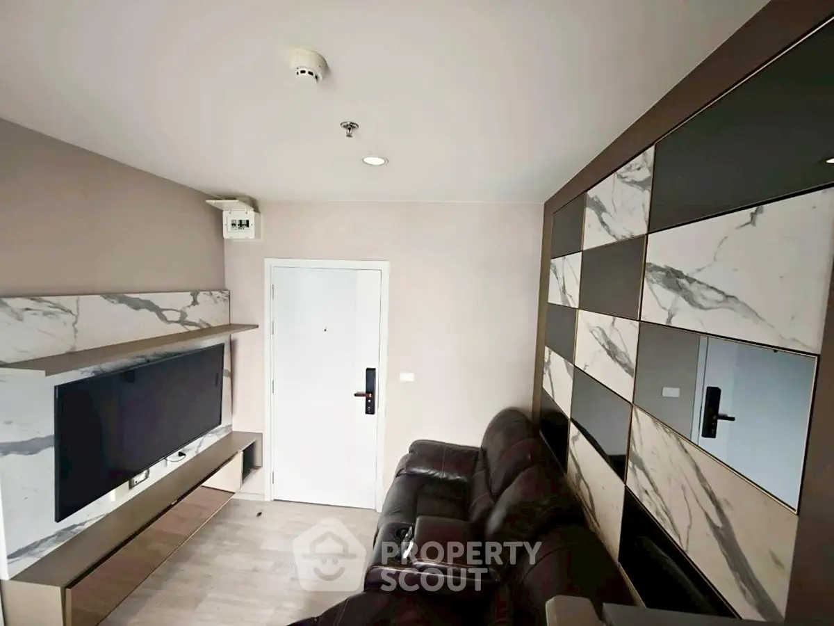 Modern living room with sleek marble accents and leather seating, featuring a wall-mounted TV and stylish storage.