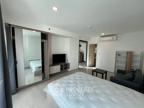 Spacious modern bedroom with mirrored wardrobe and cozy seating area