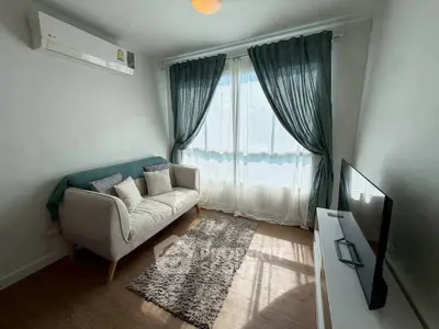 Cozy living room with natural light, stylish sofa, and modern TV setup.