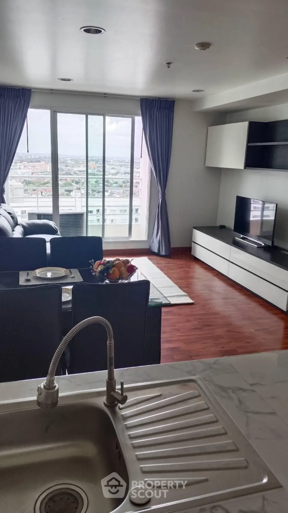 Spacious living room with modern decor and stunning city view, featuring open layout and sleek furnishings.