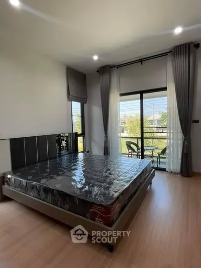 Spacious bedroom with large window and modern decor, offering a serene view of the outdoors.