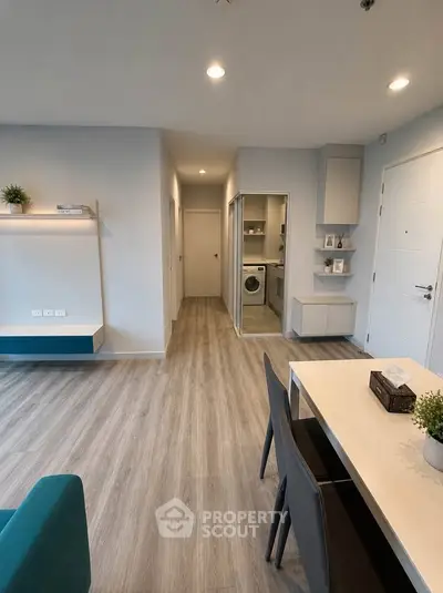 Modern apartment interior with sleek dining area and hallway leading to laundry room.