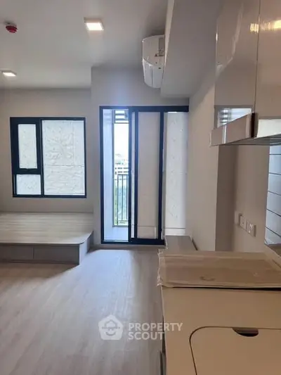 Modern apartment interior with sleek kitchen and balcony access, featuring stylish flooring and ample natural light.