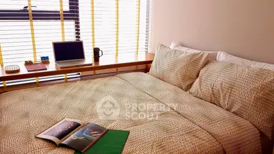 Cozy bedroom with modern decor and natural light, featuring a comfortable bed and workspace.