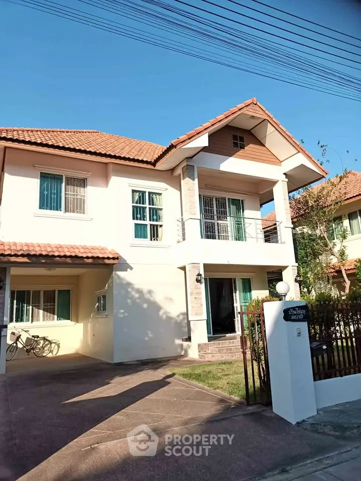 Charming two-story house with red-tiled roof and spacious driveway in sunny suburban neighborhood.