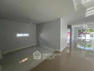 Spacious and well-lit living area with glossy tiled floors, neutral color palette, and ample natural light streaming through multiple windows, perfect for modern living.