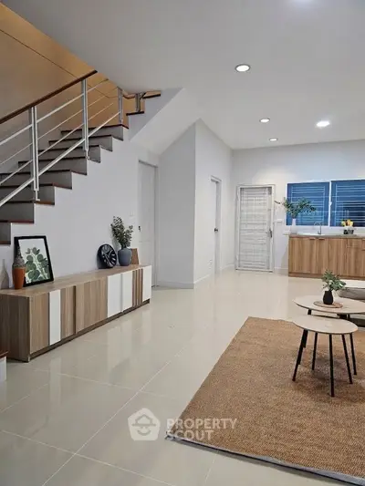 Modern living room with sleek staircase and stylish decor in a contemporary home.