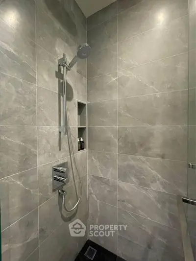 Modern bathroom with sleek gray tiles and a contemporary shower setup.