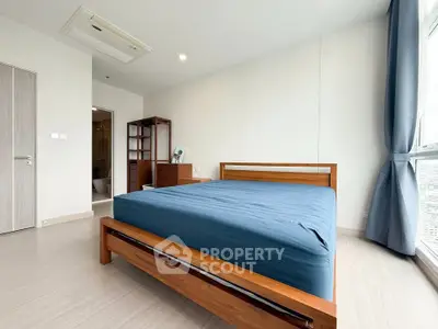 Spacious bedroom with wooden bed and large window offering city views