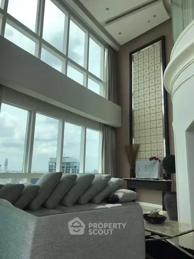 Luxurious high-ceiling living room with panoramic city views and elegant decor.