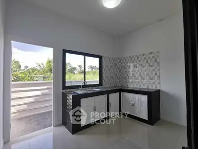 Modern kitchen with open layout and scenic view, featuring sleek cabinetry and tiled backsplash.