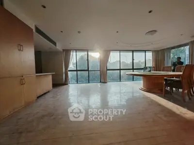 Spacious living room with large windows and elegant dining area