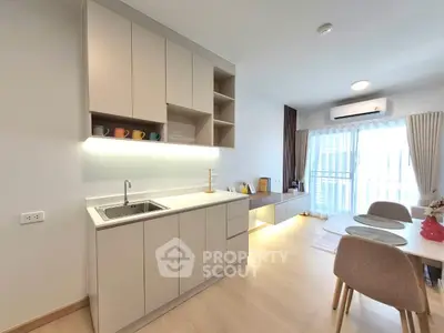 Modern kitchen with sleek cabinetry and dining area in bright apartment