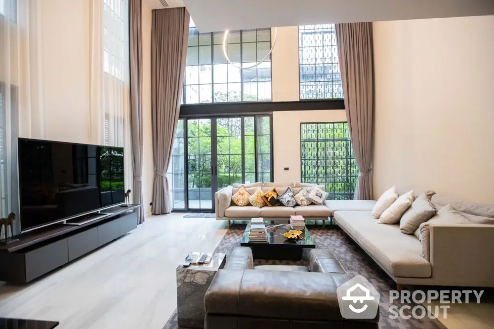 Luxurious modern living room with high ceilings and large windows offering garden views.