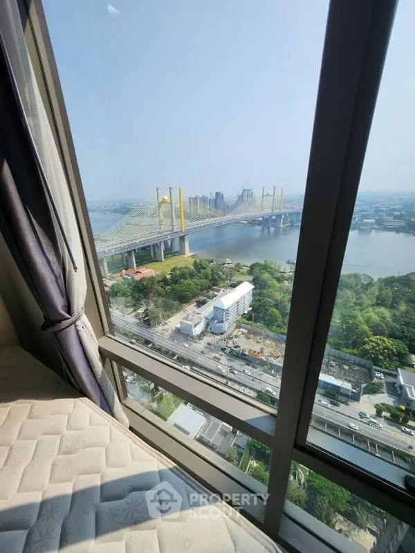 Stunning high-rise view of cityscape and river from a modern apartment window.