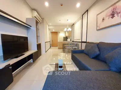 Modern living room with sleek furniture and open layout, featuring a cozy gray sofa and wall-mounted TV.