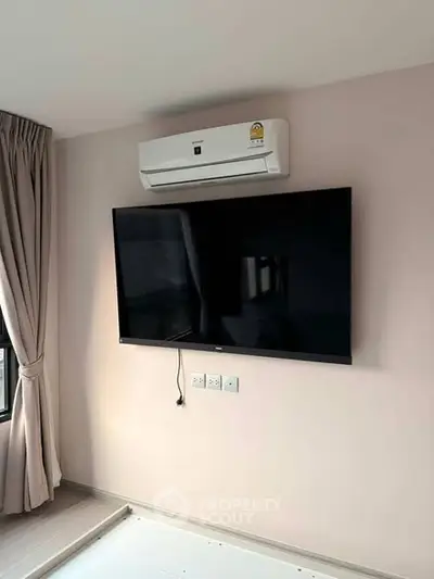Modern living room with wall-mounted TV and air conditioning unit, featuring elegant curtains.