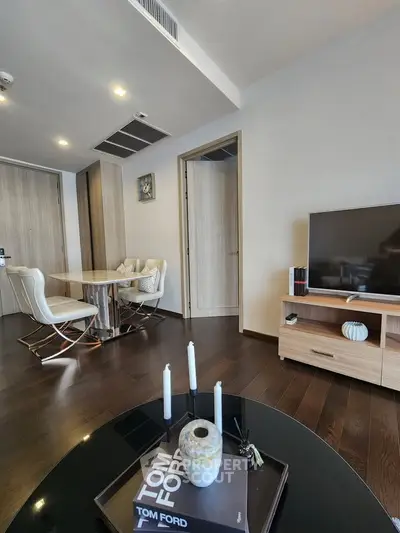 Modern living room with sleek furniture and stylish decor, featuring a TV and dining area.