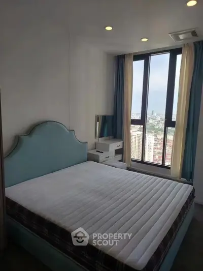 Bright bedroom with large window offering stunning city view and modern furnishings.